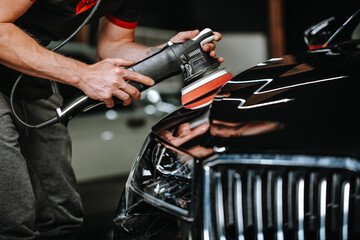 Close-up of a machine polisher restoring gloss to a car panel during paint correction